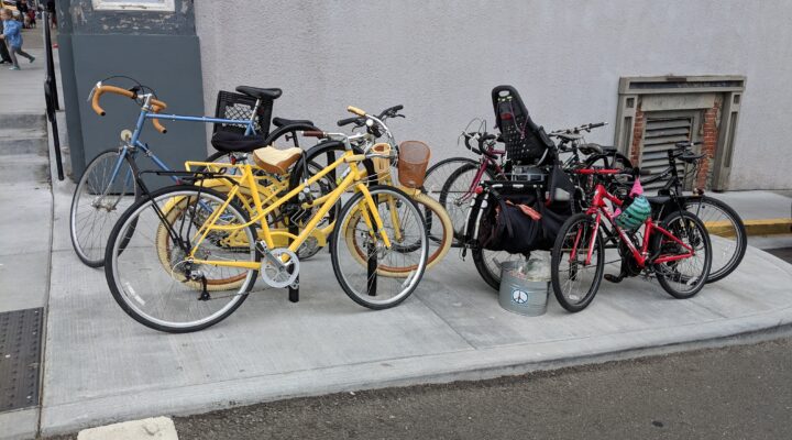 Two bike racks are covered with many locked bikes at the corner of the Arcata Plaza