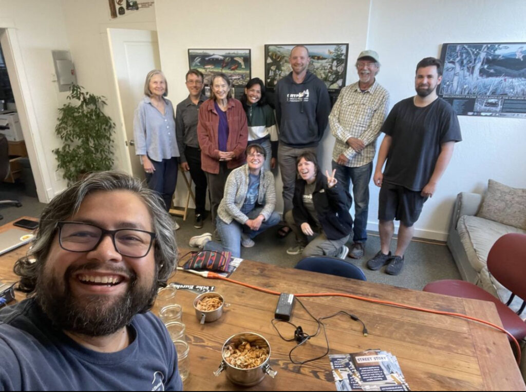 10 people gathered around a table in an office pose for a photo