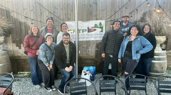 About ten people pose for a photo around a CRTP banner