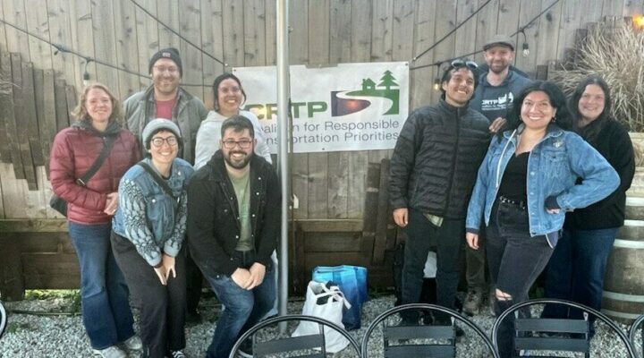 About ten people pose for a photo around a CRTP banner