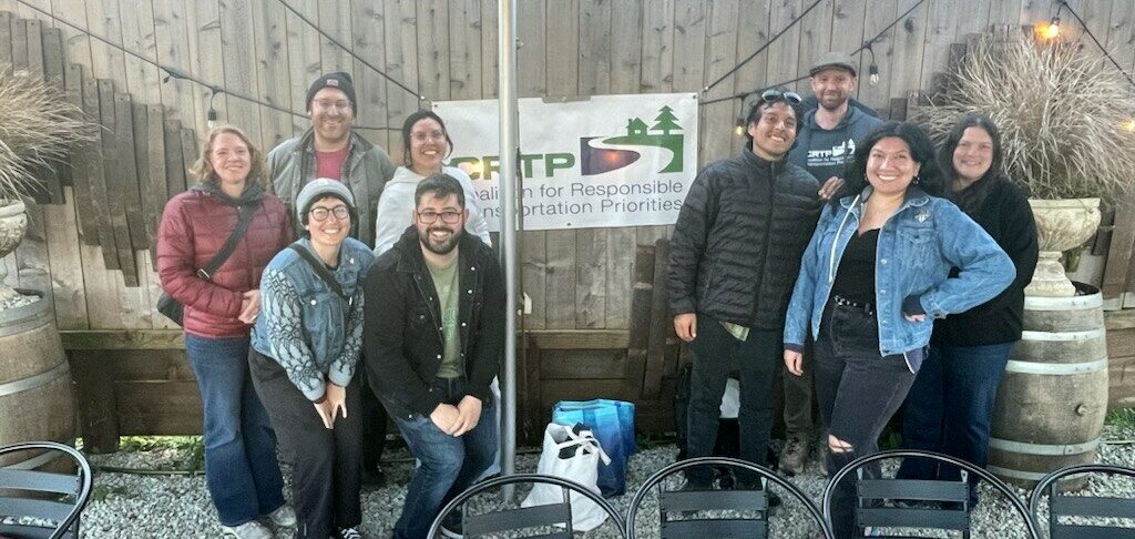 About ten people pose for a photo around a CRTP banner