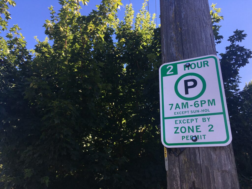 A 2-hour parking sign attached to a wooden utility pole