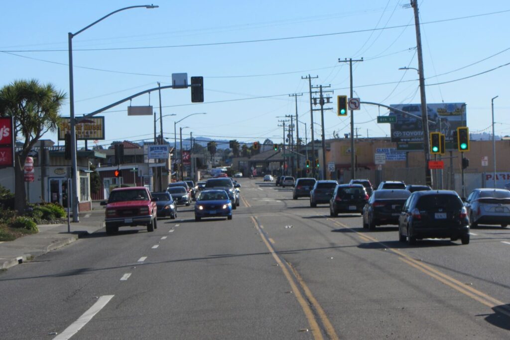 A wide four-lane road with a middle two-way turn lane is filled with cards in both directions.