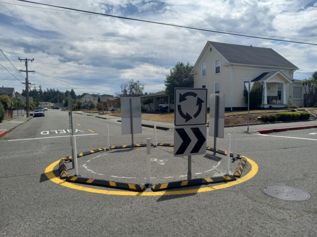 A small circle of low rubber bumpers and signs with arrows in the middle of an intersection.