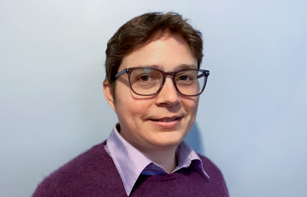 A head shot of a white woman with short brown hair and glasses.
