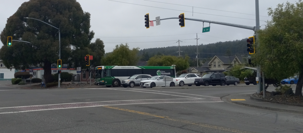 Two lines of cars and a bus wait at a traffic light
